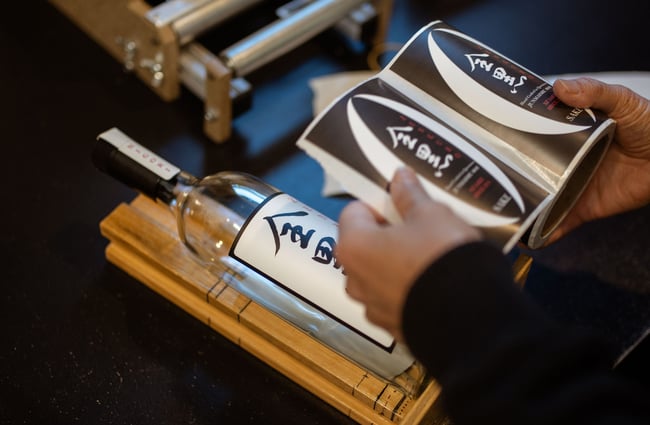 Worker adding labels to Zenkuro sake bottle