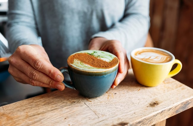 A matcha coffee and a coffee on a table.