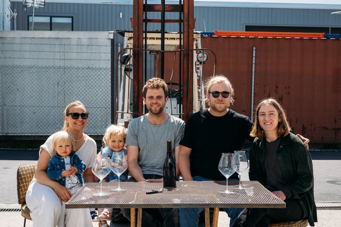 A group of adults and kids sitting down smiling to camera.