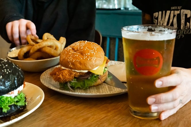 Burgers and onion rings on a table at The Burger Joint.
