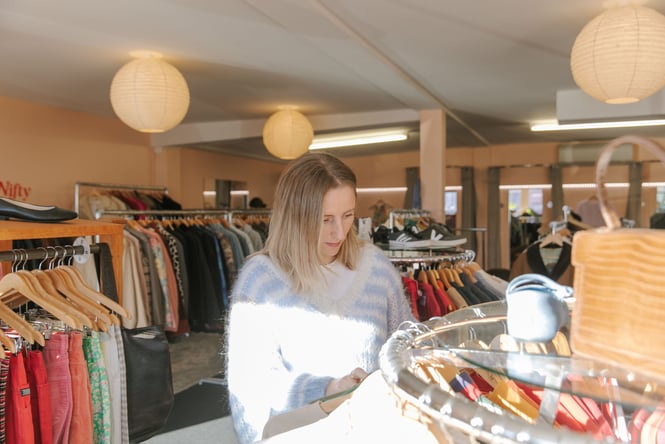 Rosie browsing through rack of secondhand clothing at Nifty in Christchurch