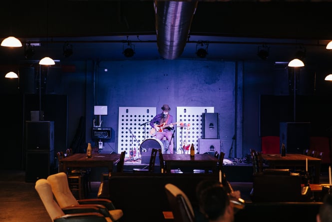 A musician plays the guitar on the small stage at 12 Bar.