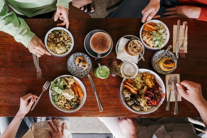 A flatlay of plates on a table with four people gathered around at Big Fig in Wānaka.