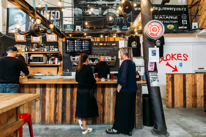Two ladies ordering at the wood panelled counter with big festoon lights hanging above them.