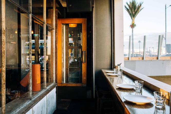 Bench top dining with palm tree in the background at Otto, Auckland.