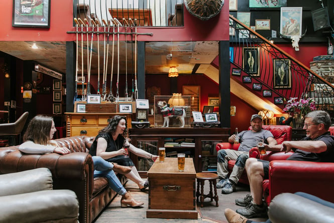 Four people sitting on couches around in a circle inside the bar at Hector Black's in Timaru.