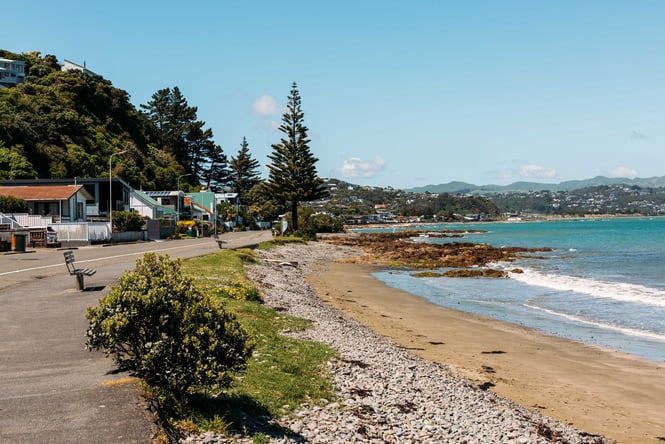 Looking across the sand covered bay where there are tree covered hills next to the beach.