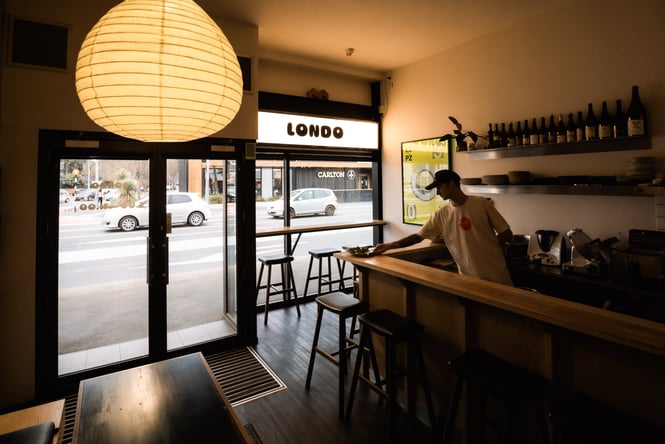 A man placing a plate of food on the counter at Londo in Christchurch.
