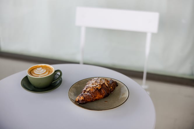 A coffee and croissant on a table.