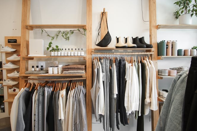 Clothes, shoes and bottles hung on wooden display racks and shelves.
