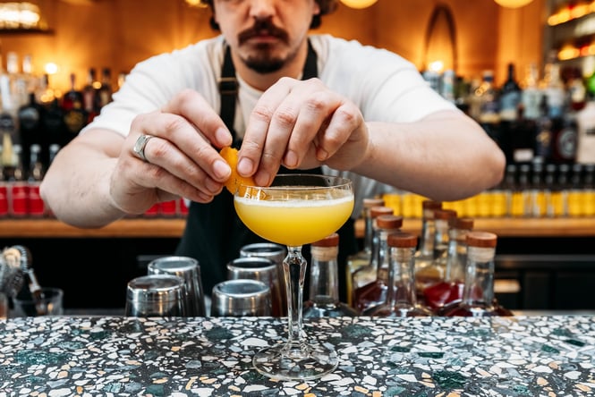 Close up of a bartender garnishing a cocktail.