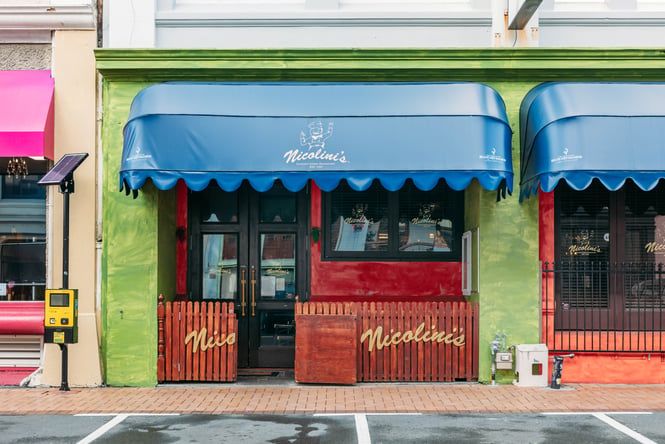 Green building exterior of Nicolini's and blue awning.