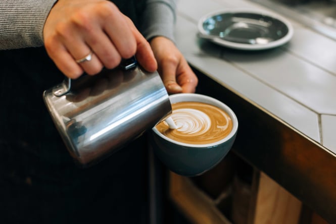 Pouring steamed milk into coffee cup at Ozone Coffee Roasters, New Plymouth.