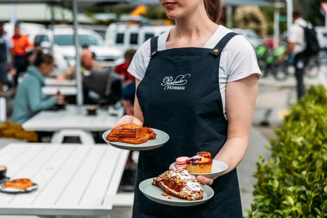 Staff member holding three plates of pastries at Pembroke Pâtisserie.