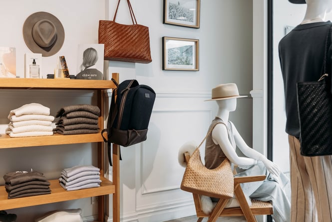 Folded knitwear on wooden shelves and mannequins accessorised with hats and woven shoulder bags.