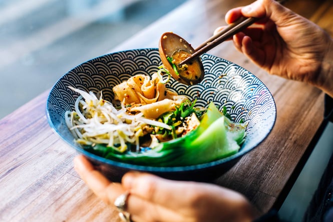 Woman eating noodle bowl.