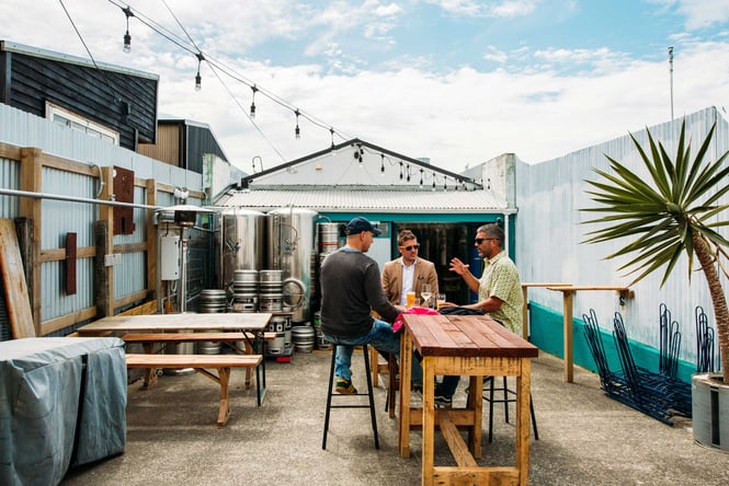 The outside courtyard at The Beer Engine where three guys are sitting around a table drinking beer.