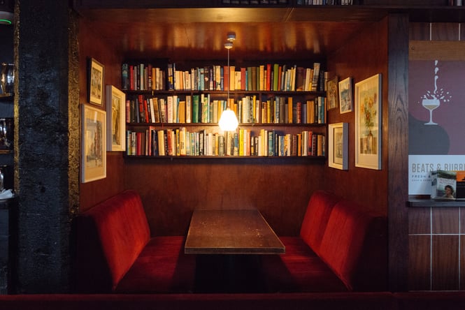 A booth beneath a shelves of books at The Library bar Wellington.