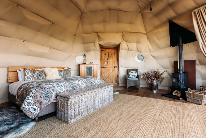 A bedroom set inside a Glamping pod with a wooden panelled floor.