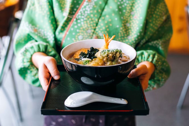A waitress holding a bowl of food.