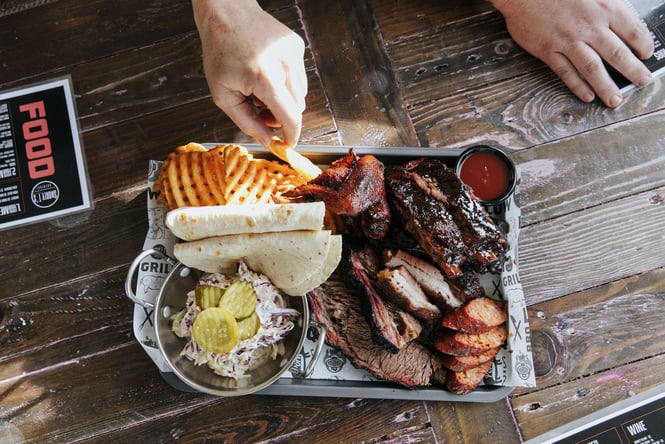 Someone reaching for a chip from a plate of bbq meats at Smokey T's