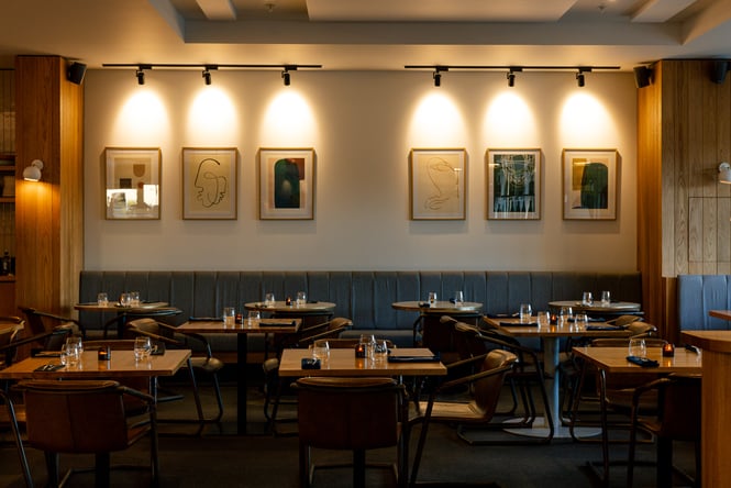 Contemporary dining area at Earl in Christchurch with leather seating and modern art lined up on main wall
