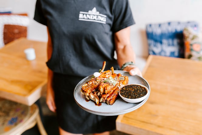 A woman holding a plate of Indonesian flavoured ribs.