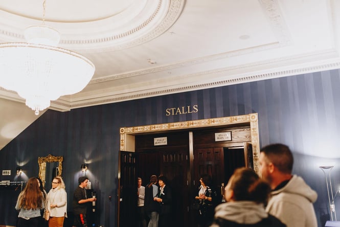 People standing around inside Isaac Theatre Royal in the evening.
