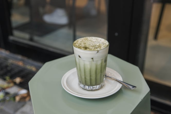 Iced matcha einspänner served in a glass atop a green stool