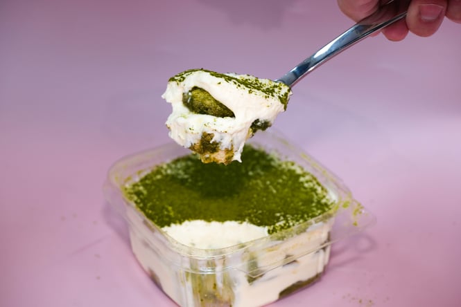 Small box of matcha tiramisu set against a pink backdrop