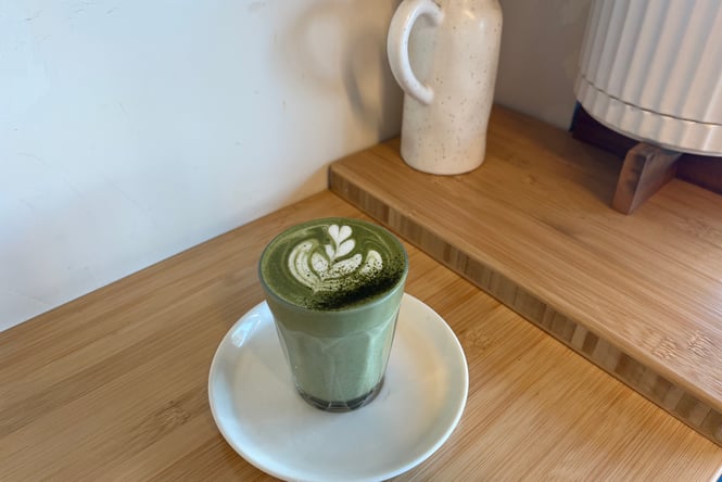 Matcha latte served in a glass on a wooden cafe table