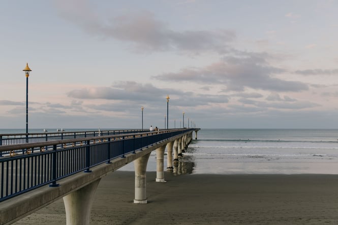 Looking out across New Brighton Pier and the ocean in the evening with pinky purple skies