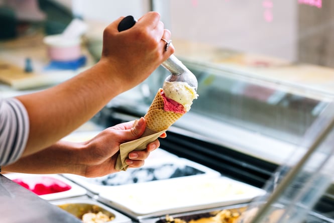 Ice cream being scooped into a cone.