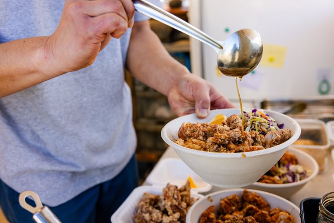 Broth being ladled on top of a bowl of food.