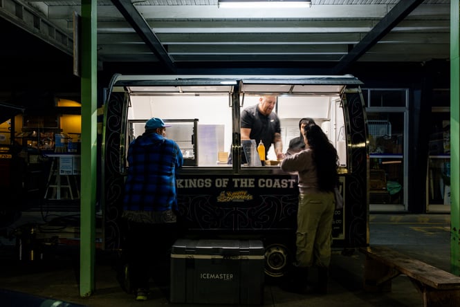 Customers being at a food truck window in the evening.