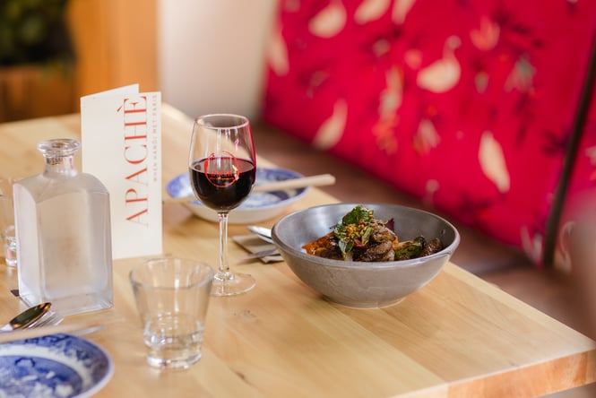 Shaking beef dish and glass of red wine on the table at Apache.