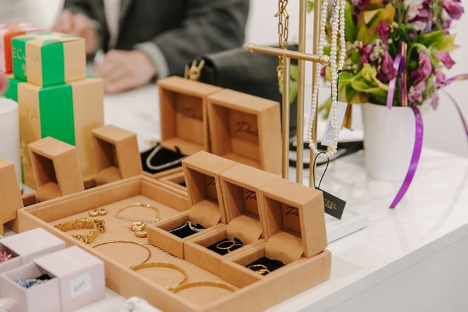 Gold and silver jewellery displayed in suede-lined beige boxes and trays.
