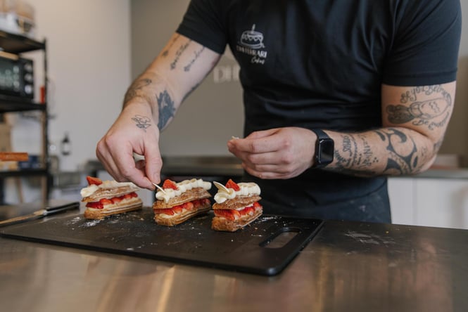 Close up of pastry chef adding the final touches to a strawberry eclair