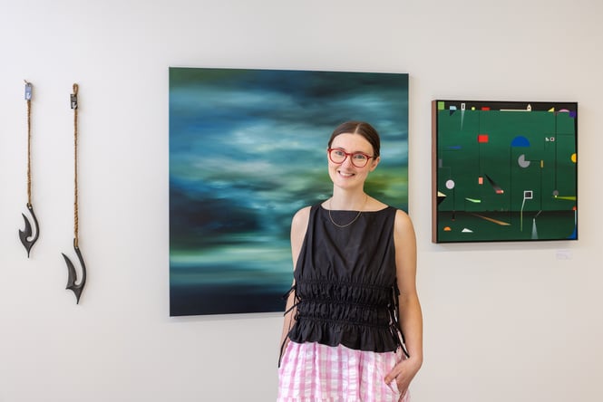 Ashleigh Thompson standing in front of artwork at her gallery Ashe in Christchurch
