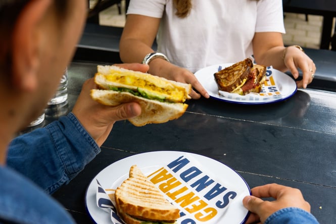 Person holding up half of a sandwich from Central Deli on New Regent Street