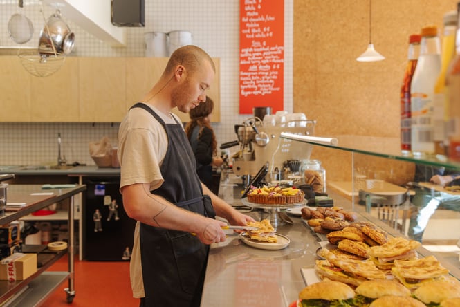 Staff at Peaches reaching into cabinet of sandwiches with tongs