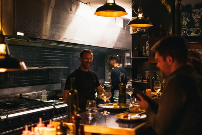 The chef behind the counter smiling while serving customers.