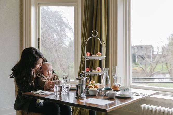 A mum and baby sitting at a table at Mona Vale enjoying a high tea.