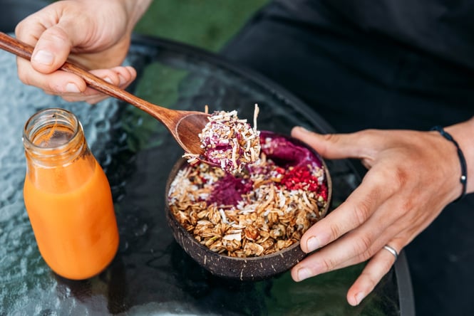 Customer's spoon is in a colourful smoothie bowl with a juice next to it on the table at Dripping Bowl.