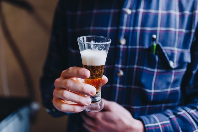 A man holding a small beer in his hand.