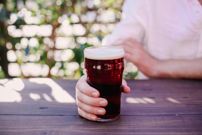 A hand holding a pint of beer.
