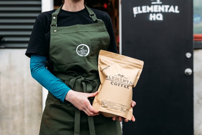 Staff member holding a bag of coffee beans at Elemental.