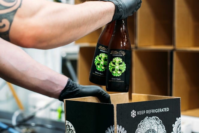 Staff member pulling out bottles of a box at Little City Kombucha.
