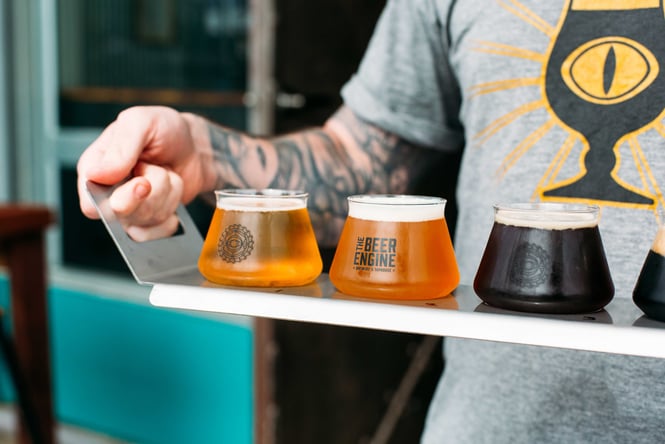 Customer carrying a tasting tray of beers at The Beer Engine.