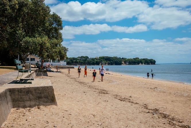 People walking along the shoreline at Cheltenham Beach.